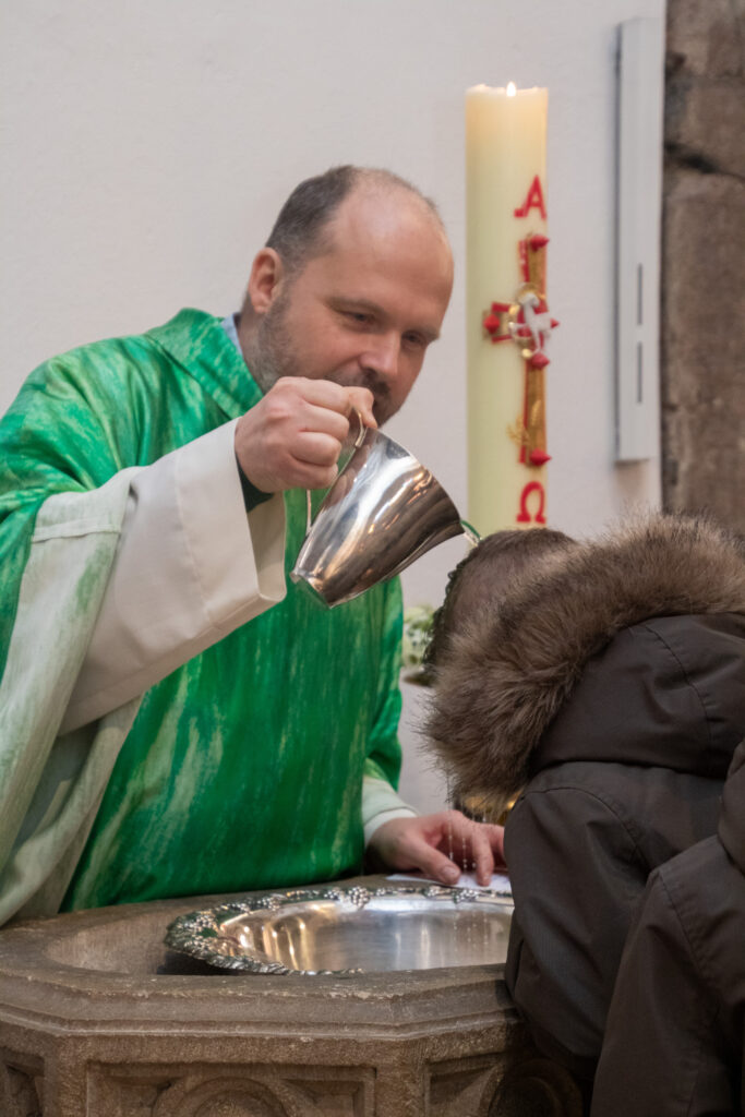 Übergießen des Kopfes eines Kindes mit Wasser